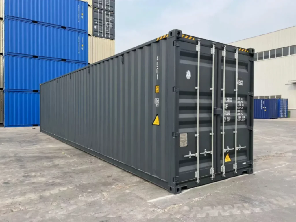 New 40ft high cube shipping container in dark grey, closed doors visible, stacked blue containers in background.