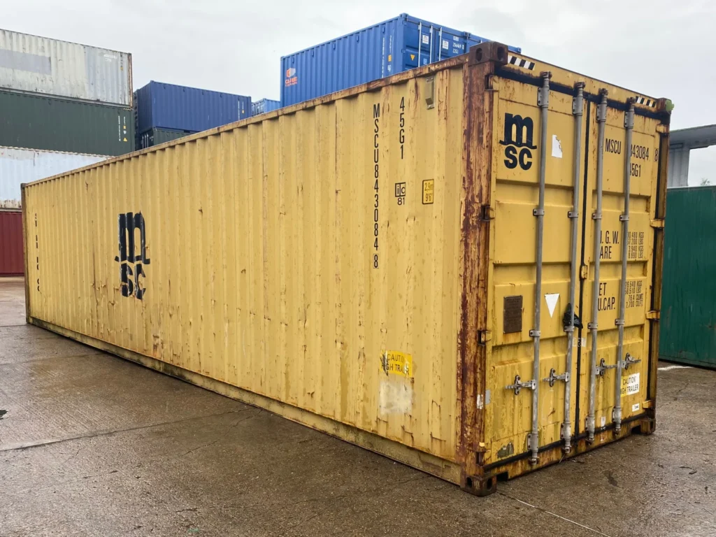 40ft used high cube shipping container in yellow with visible rust, stacked among other containers in a storage yard.