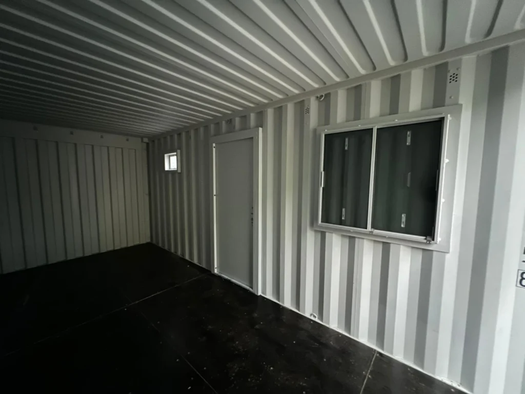 Converted shipping container interior with fitted door and windows
