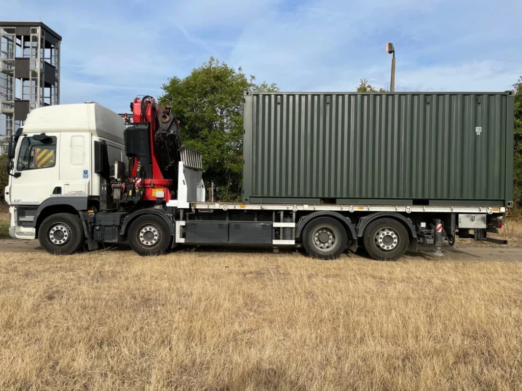 HIAB truck transporting shipping container on flatbed trailer