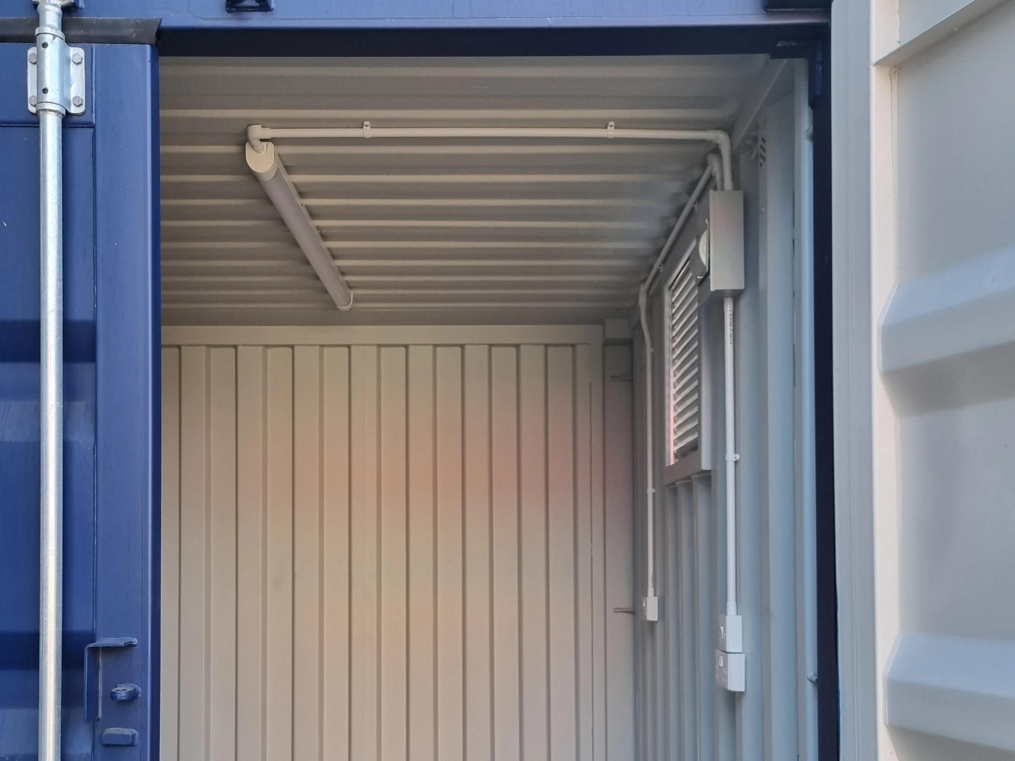Shipping container interior fitted with electrics and ceiling light