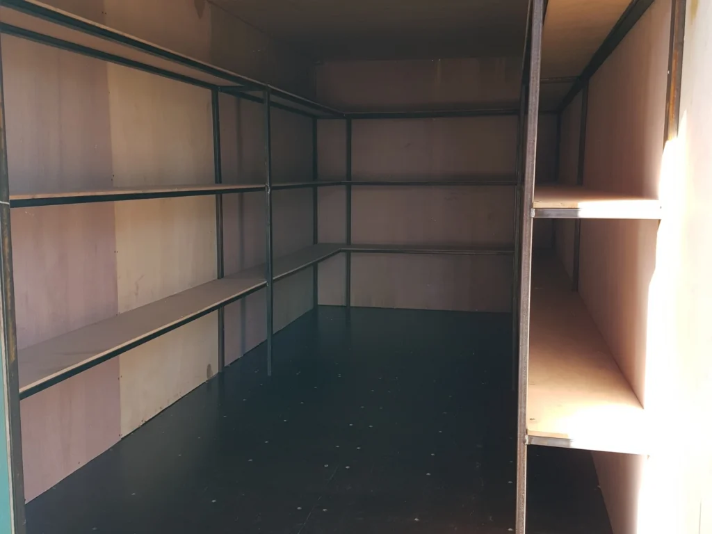 Shipping container interior fitted with shelving units for organised storage