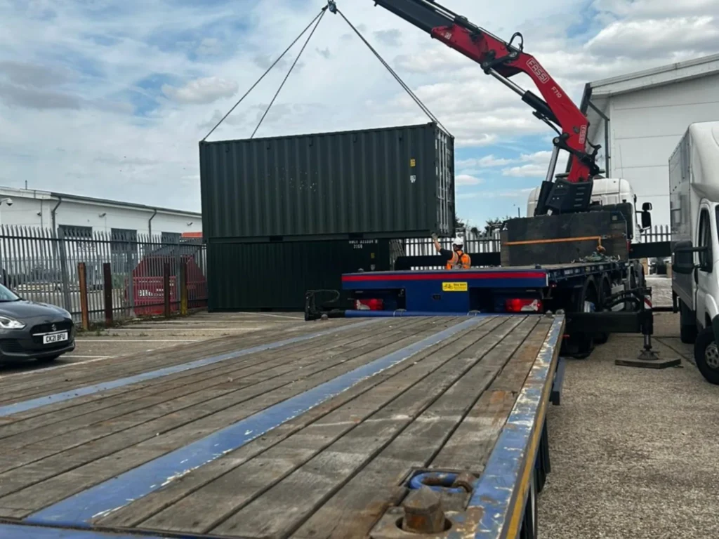 20ft new shipping container in RAL 6007 green being delivered on a wagon and drag vehicle