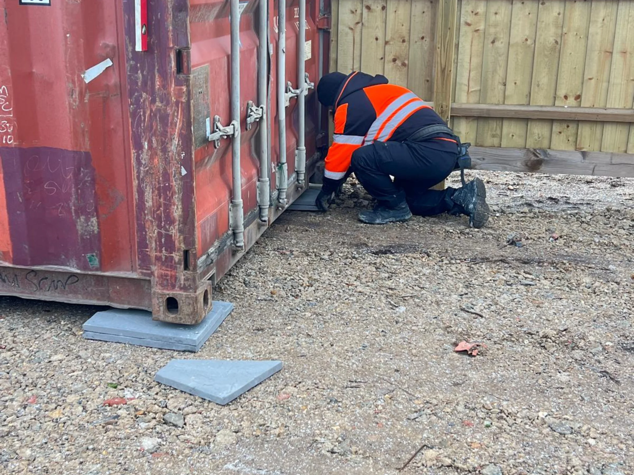 Shipping container being levelled on concrete paving slabs during delivery to prevent door racking and extend lifespan