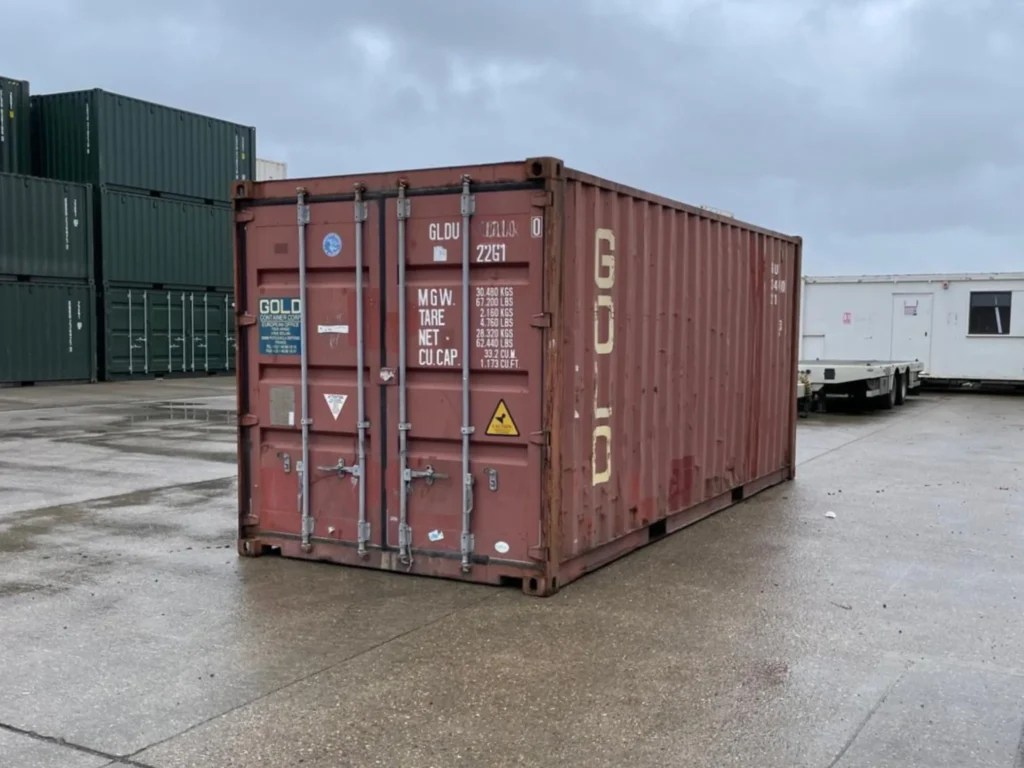 Angled front view of a red 20ft shipping container at a UK container yard