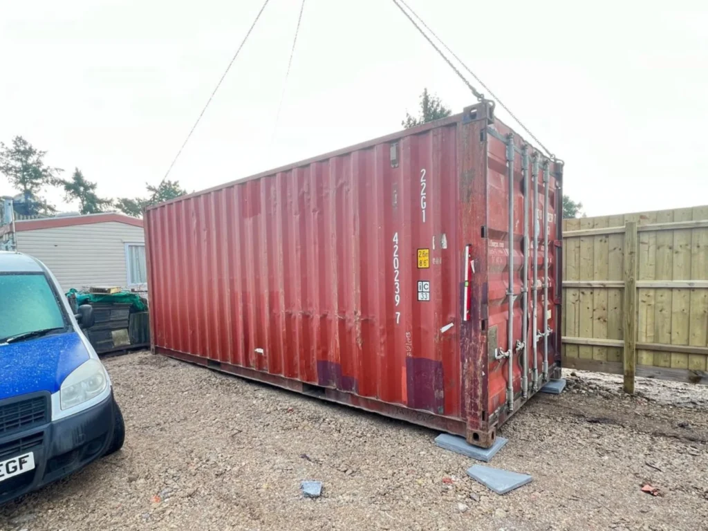 Common Problems with Used Shipping Containers (and How to Avoid Them) Hiab lorry delivering a shipping container with stabiliser outriggers deployed for safe lifting