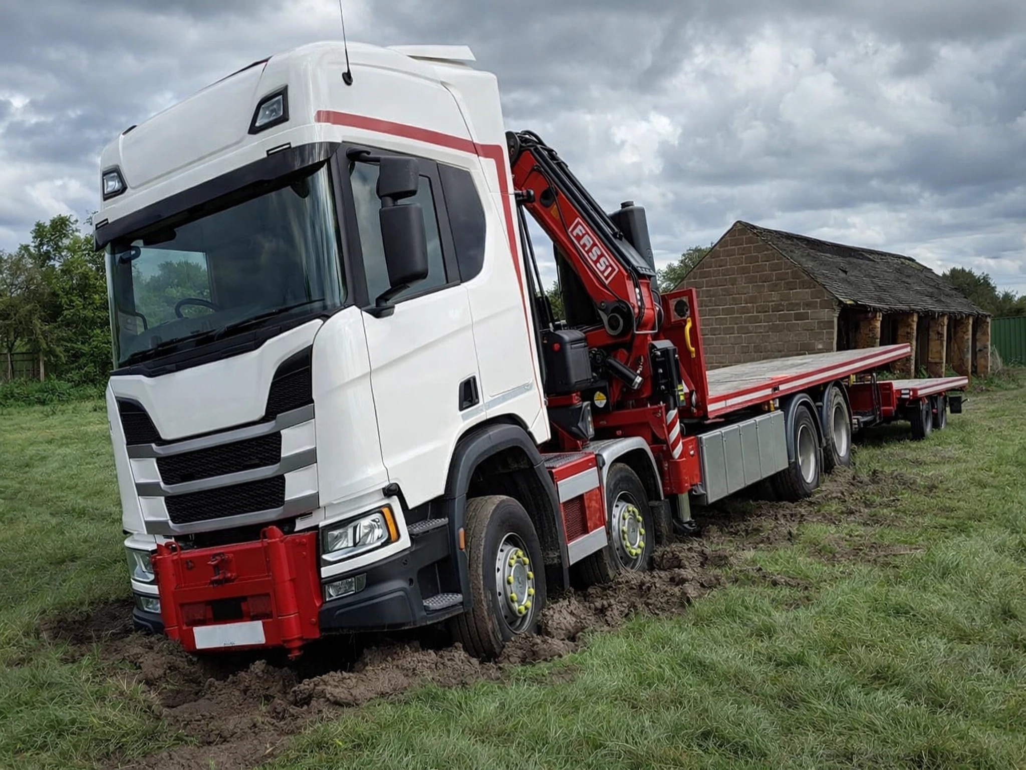 HIAB shipping container lorry sinking into soft grass during UK site delivery, showing why firm ground preparation is essential